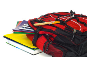 Red backpack overflowing with school supplies including pencils rulers folders and books